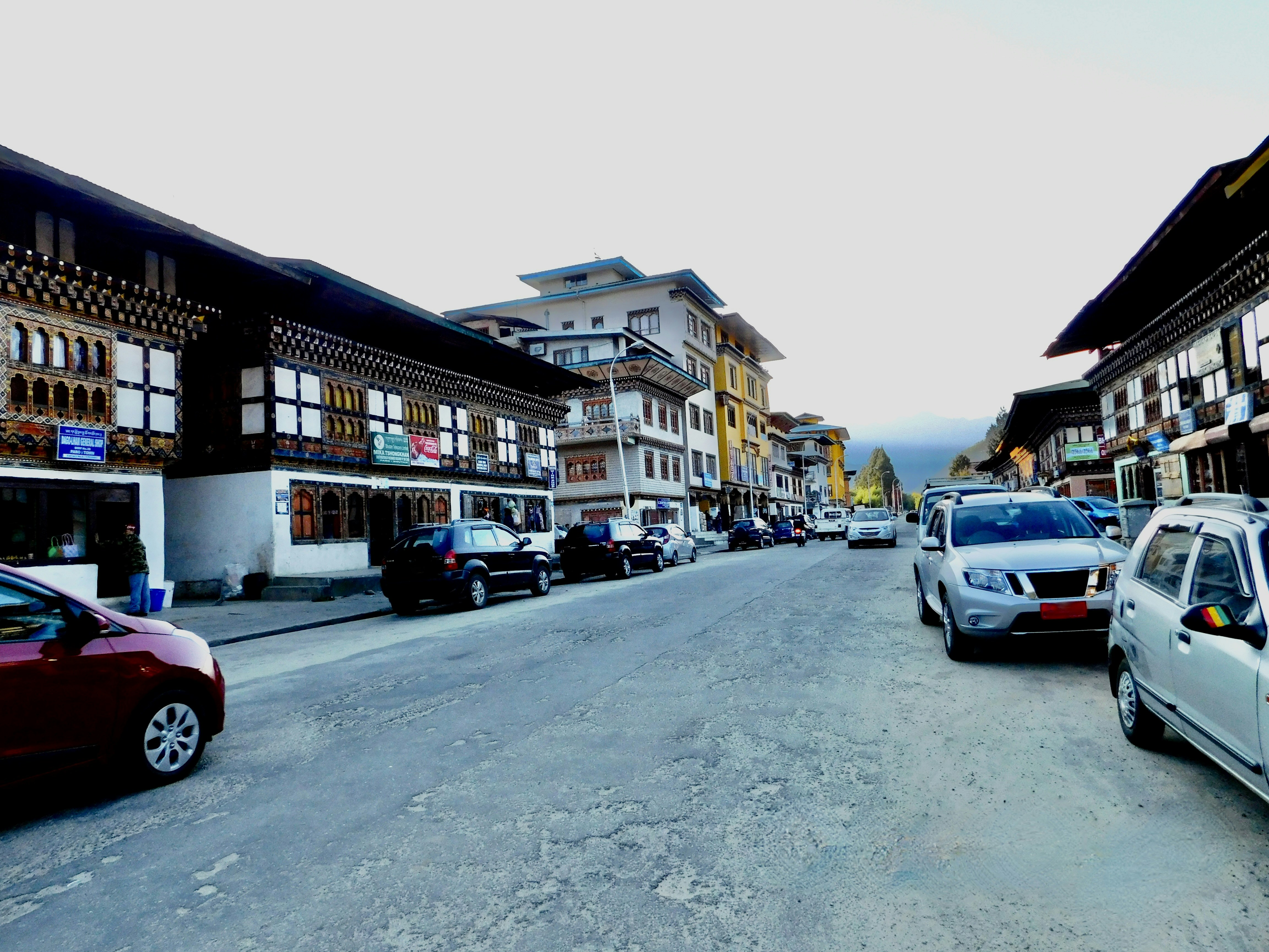 a street with cars parked along it, A busy road in the capital of Bhutan,Thimpu.