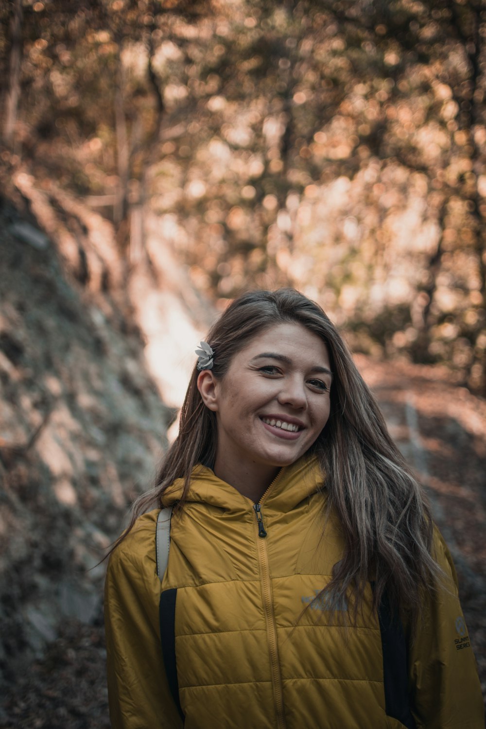 a person smiling in front of a tree with fall leaves