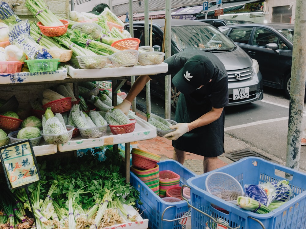 Una persona parada junto a una mesa llena de verduras