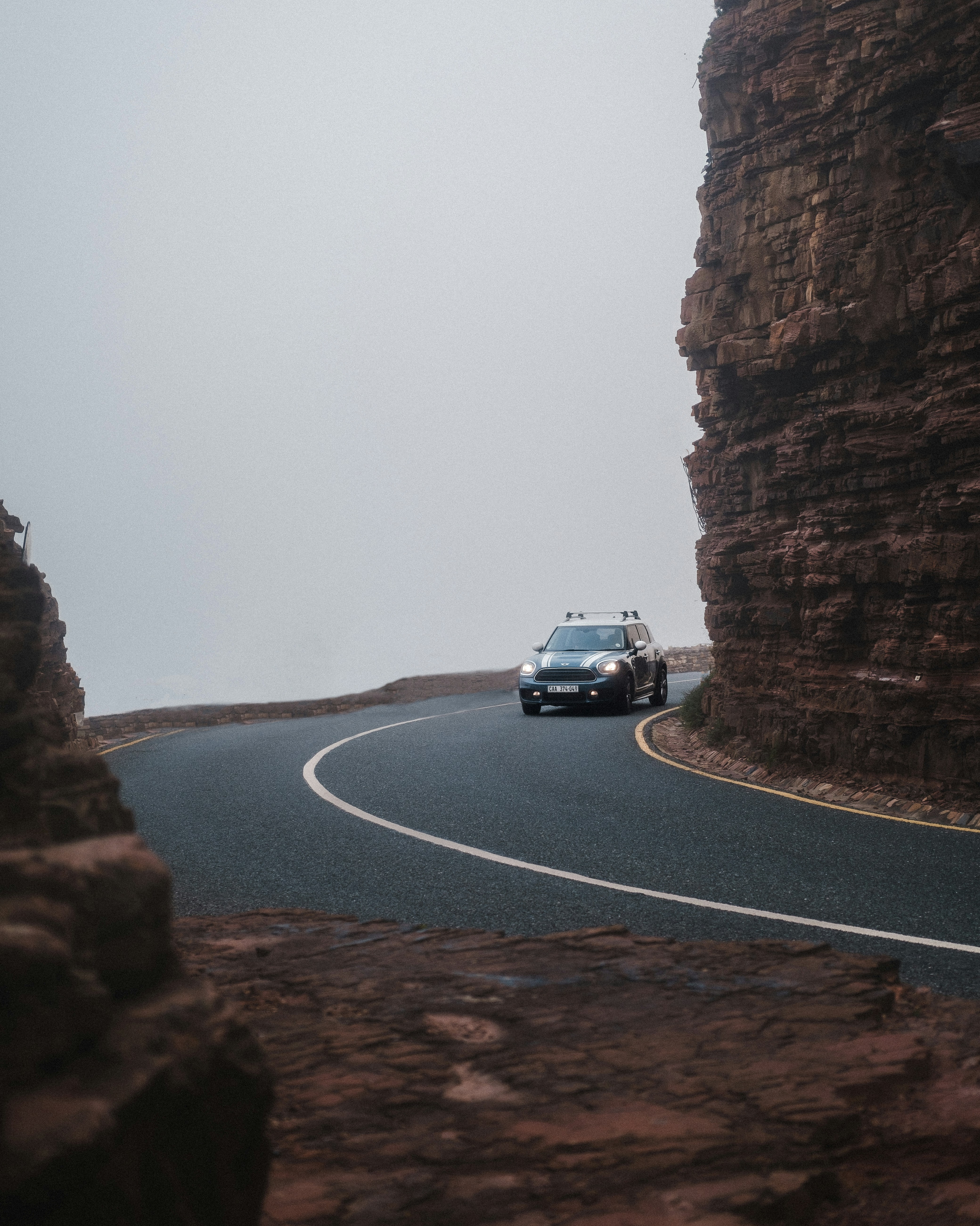 a car driving on a road between large rocks