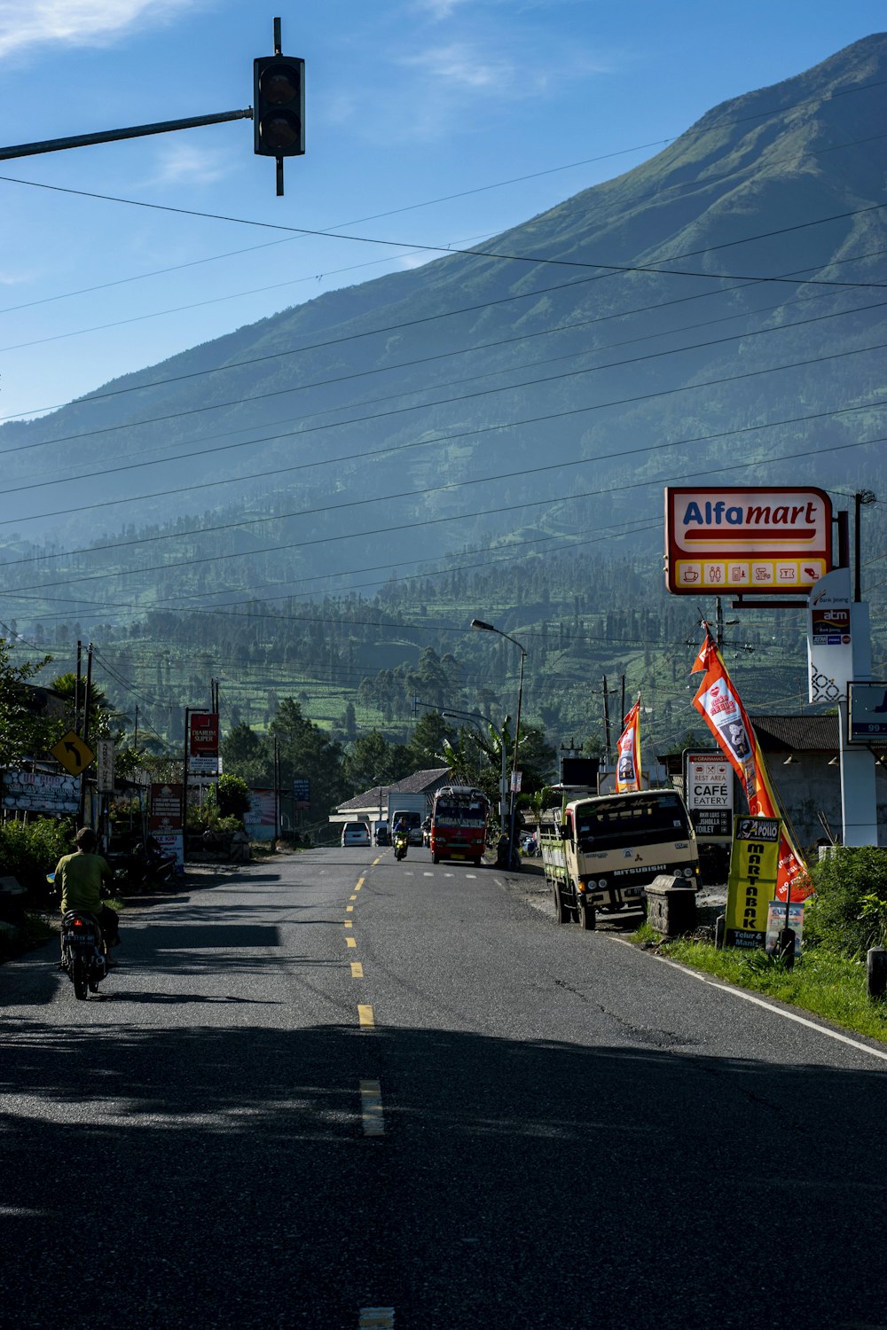 a person riding a bicycle on a road with a mountain in the background