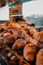 Freshly baked golden croissants and bread displayed in a cozy bakery case.