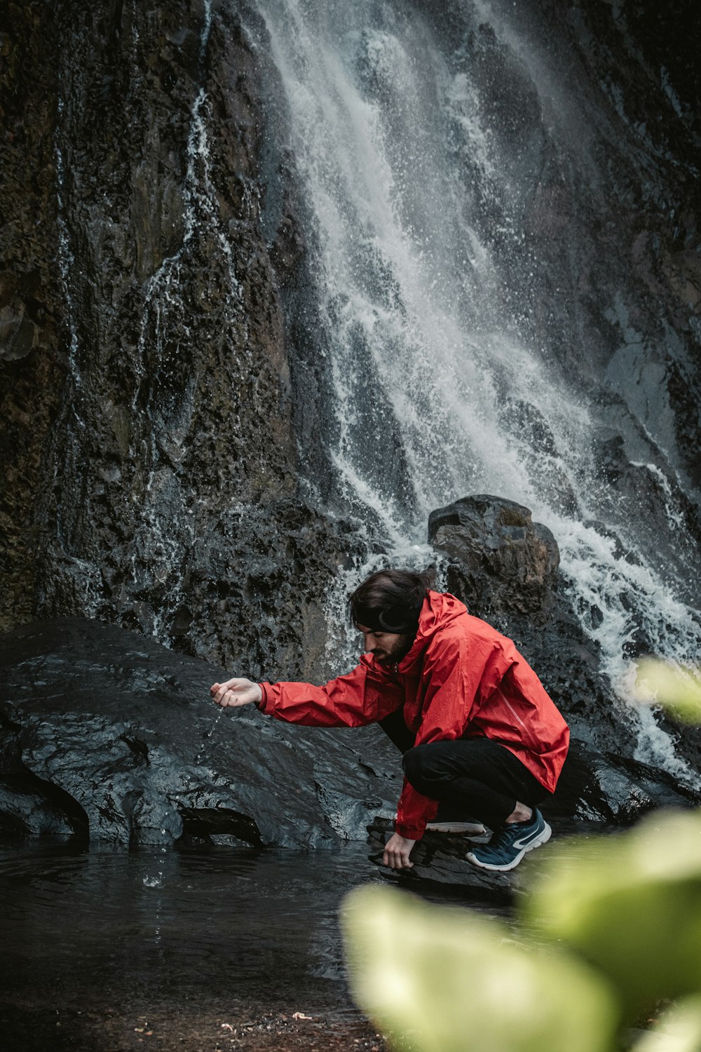 a man kneeling in front of a waterfall