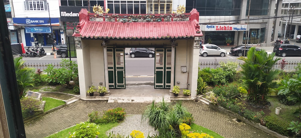 um pequeno edifício com um toldo vermelho e plantas na frente dele