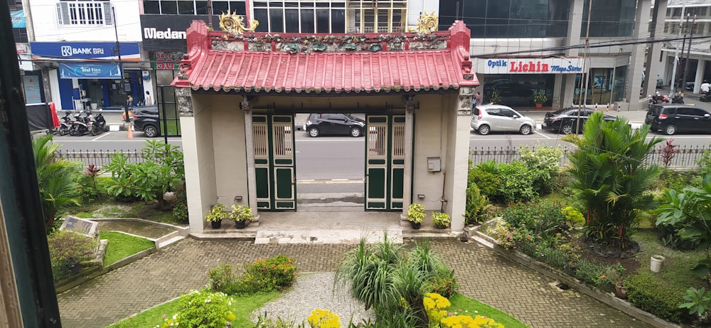 a small building with a red awning and plants in front of it