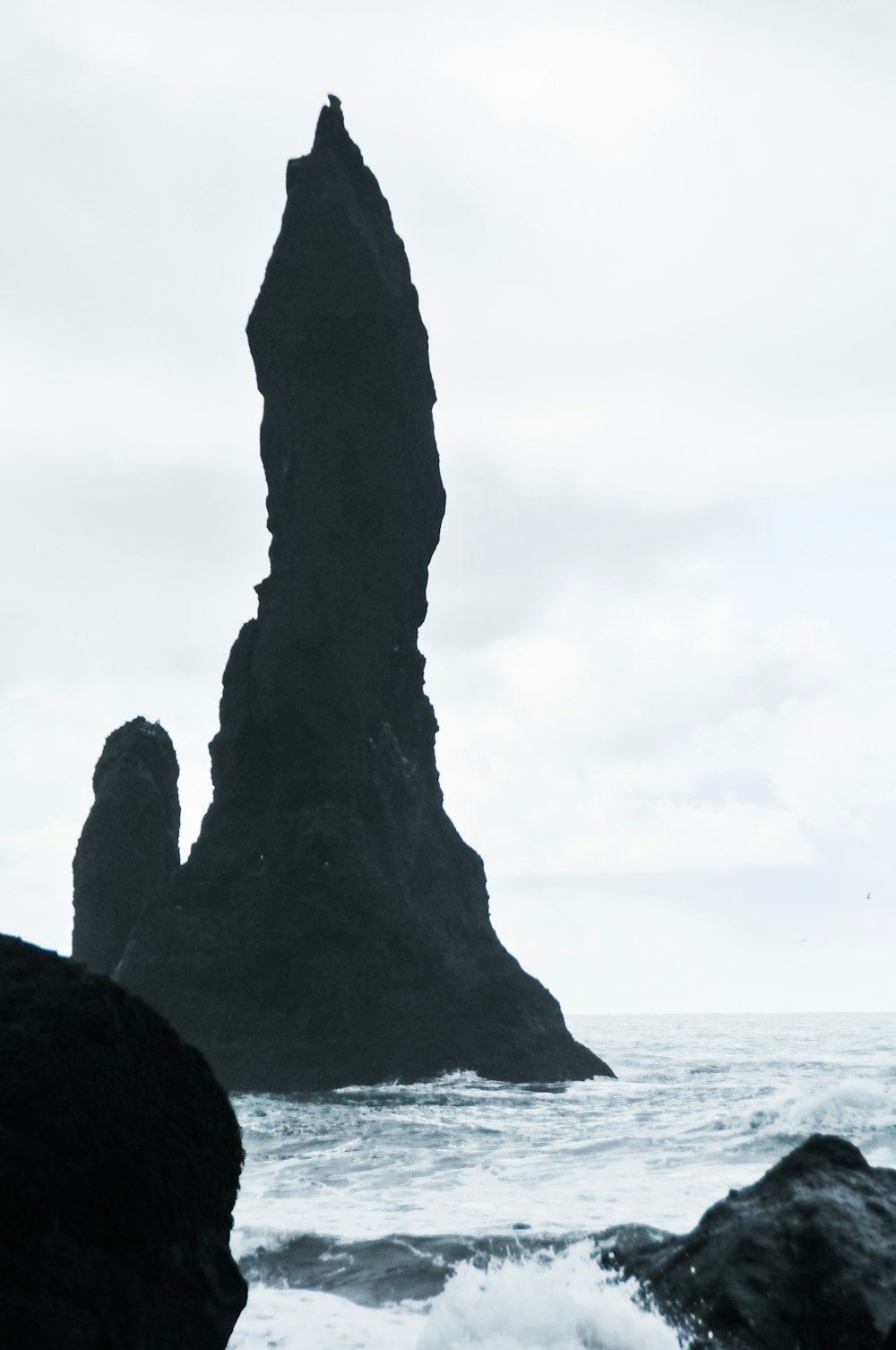 une personne debout devant un gros rocher