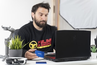 a man sitting at a desk with a laptop and a microphone
