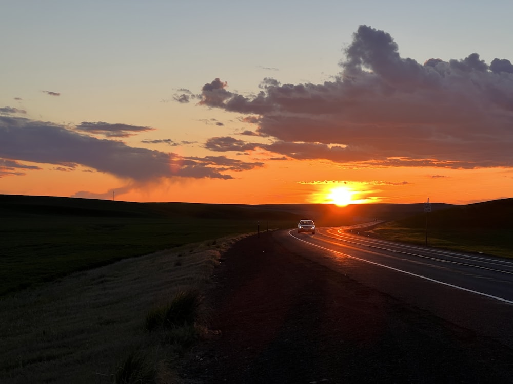 a car driving down a road at sunset