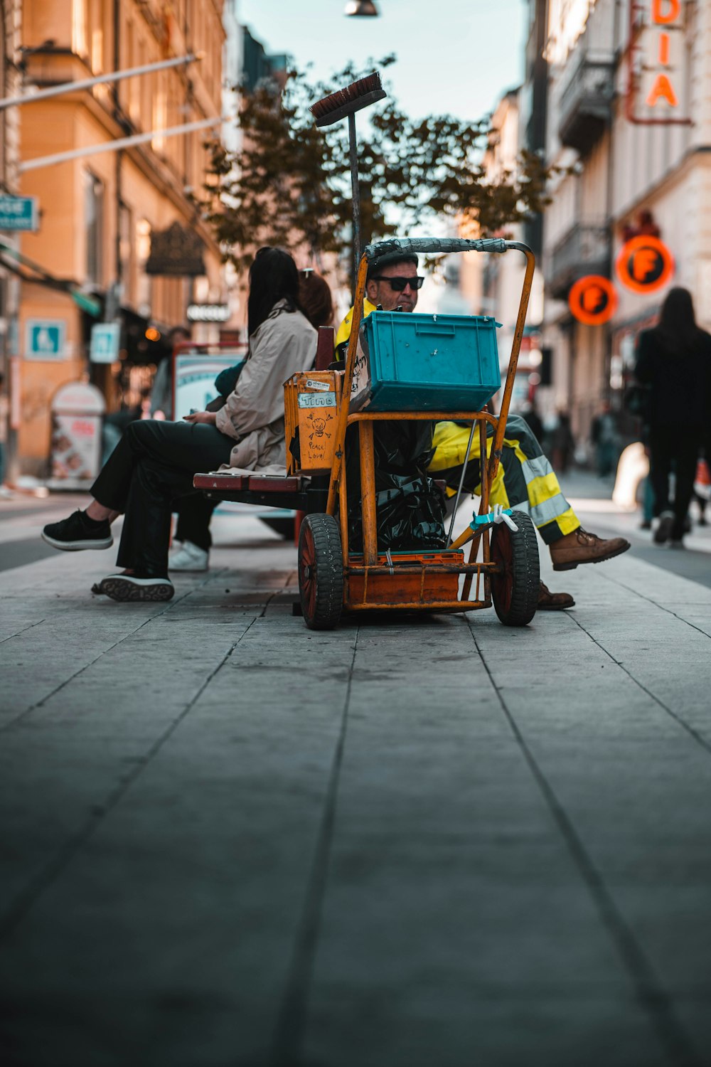 a man and woman sitting on a bench next to a cart