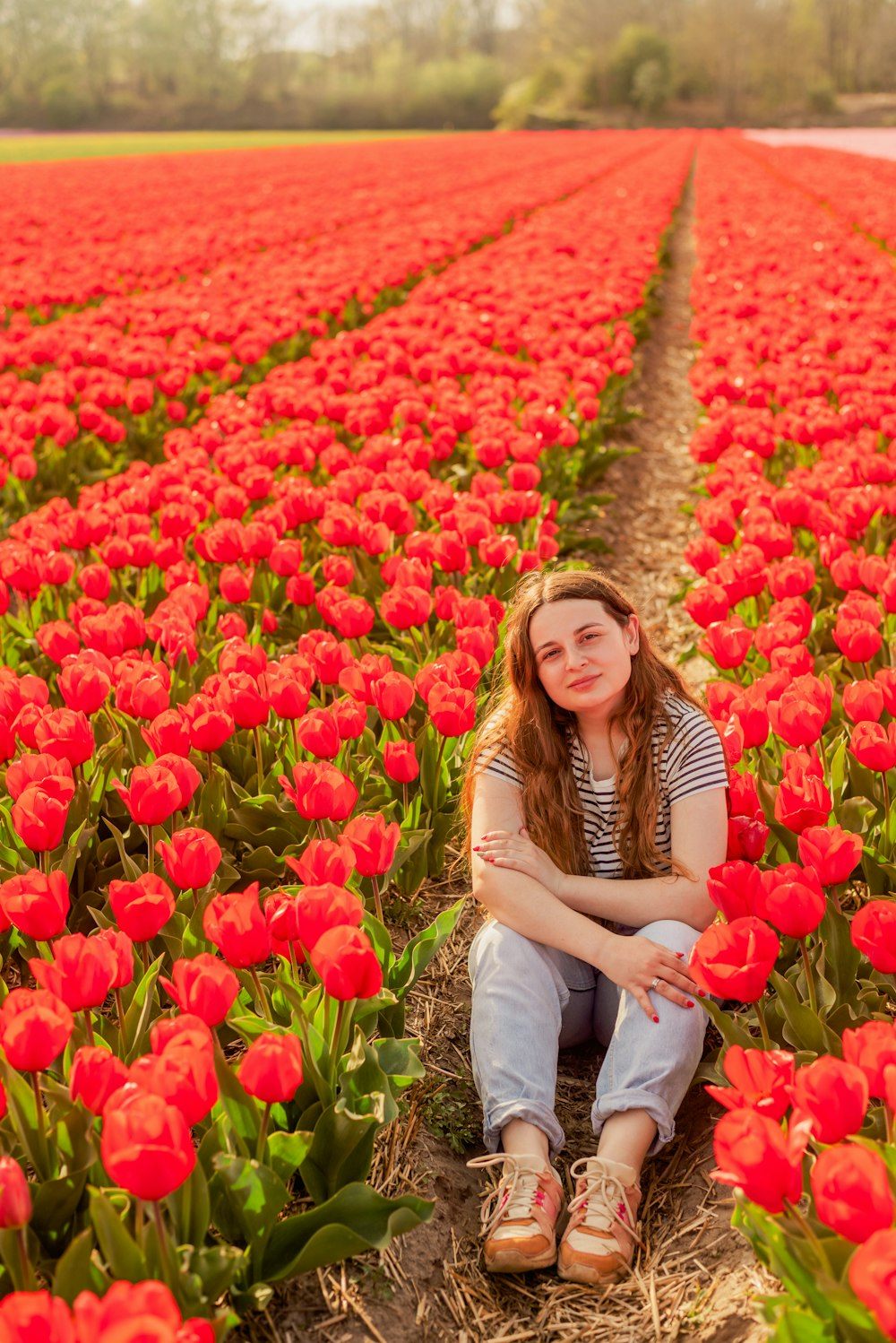 a woman sitting in a field of red flowers