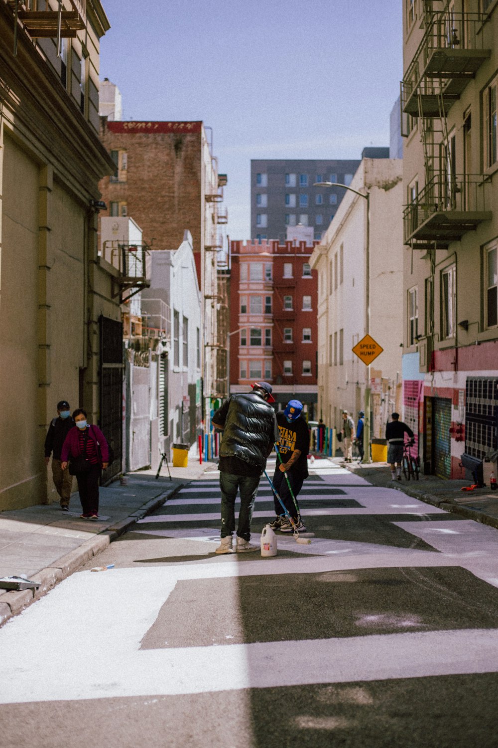 um grupo de pessoas andando por uma rua com edifícios de ambos os lados