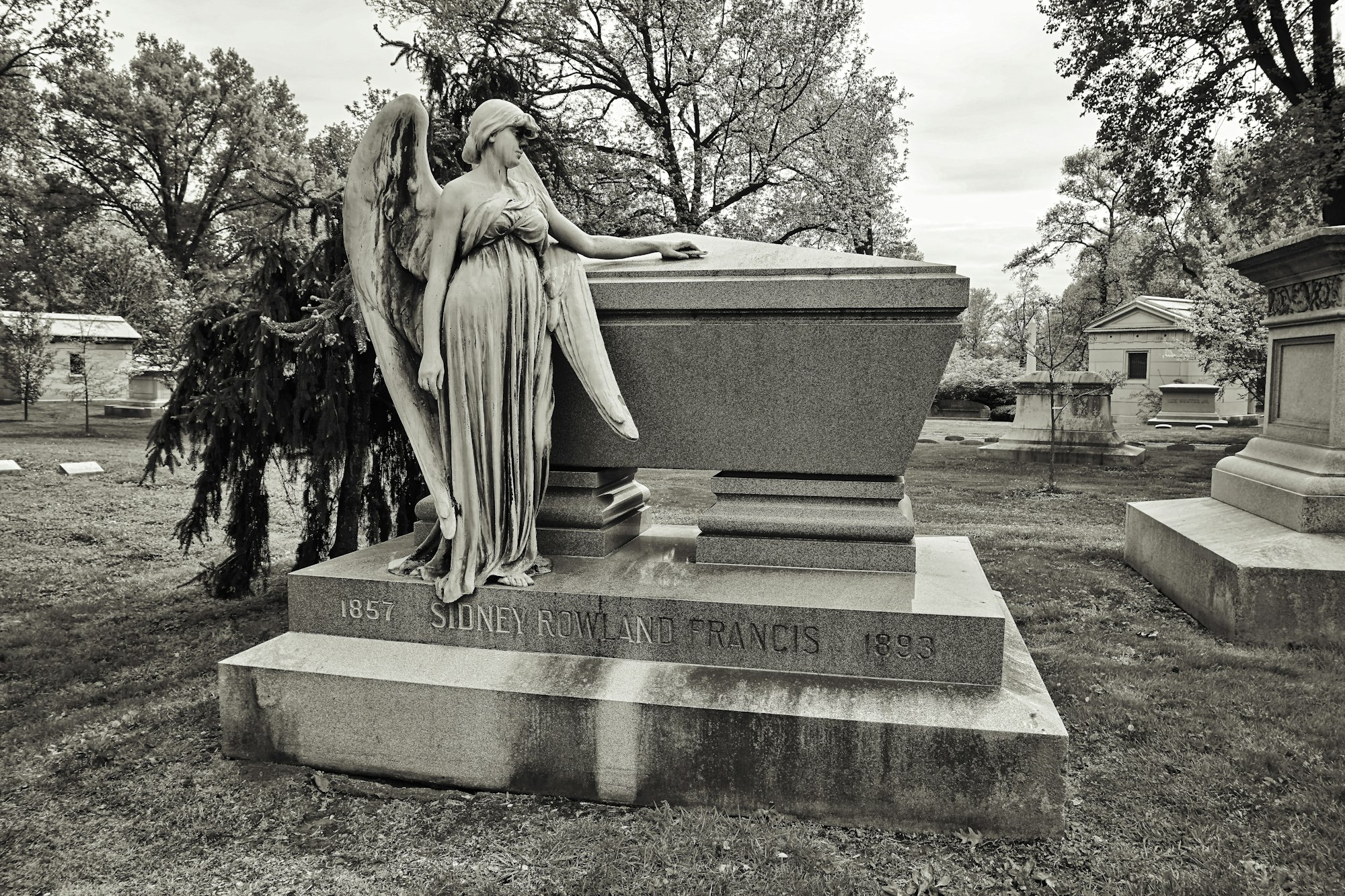 a statue of a person sitting on a bench in a park