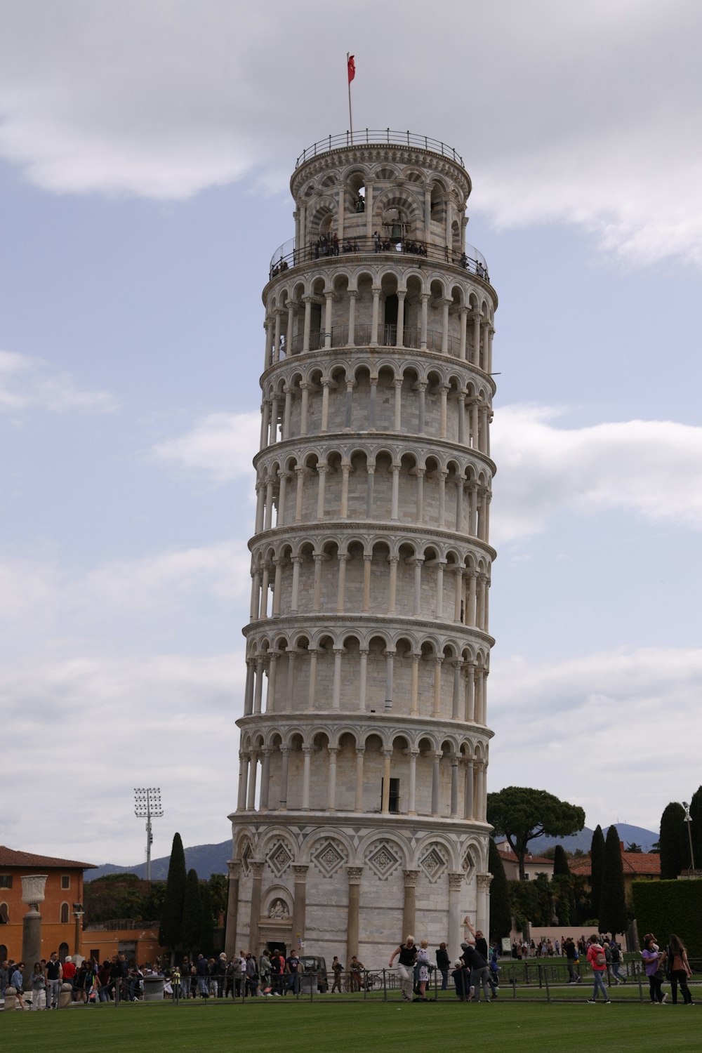 a tall tower with people around it with Leaning Tower of Pisa in the background