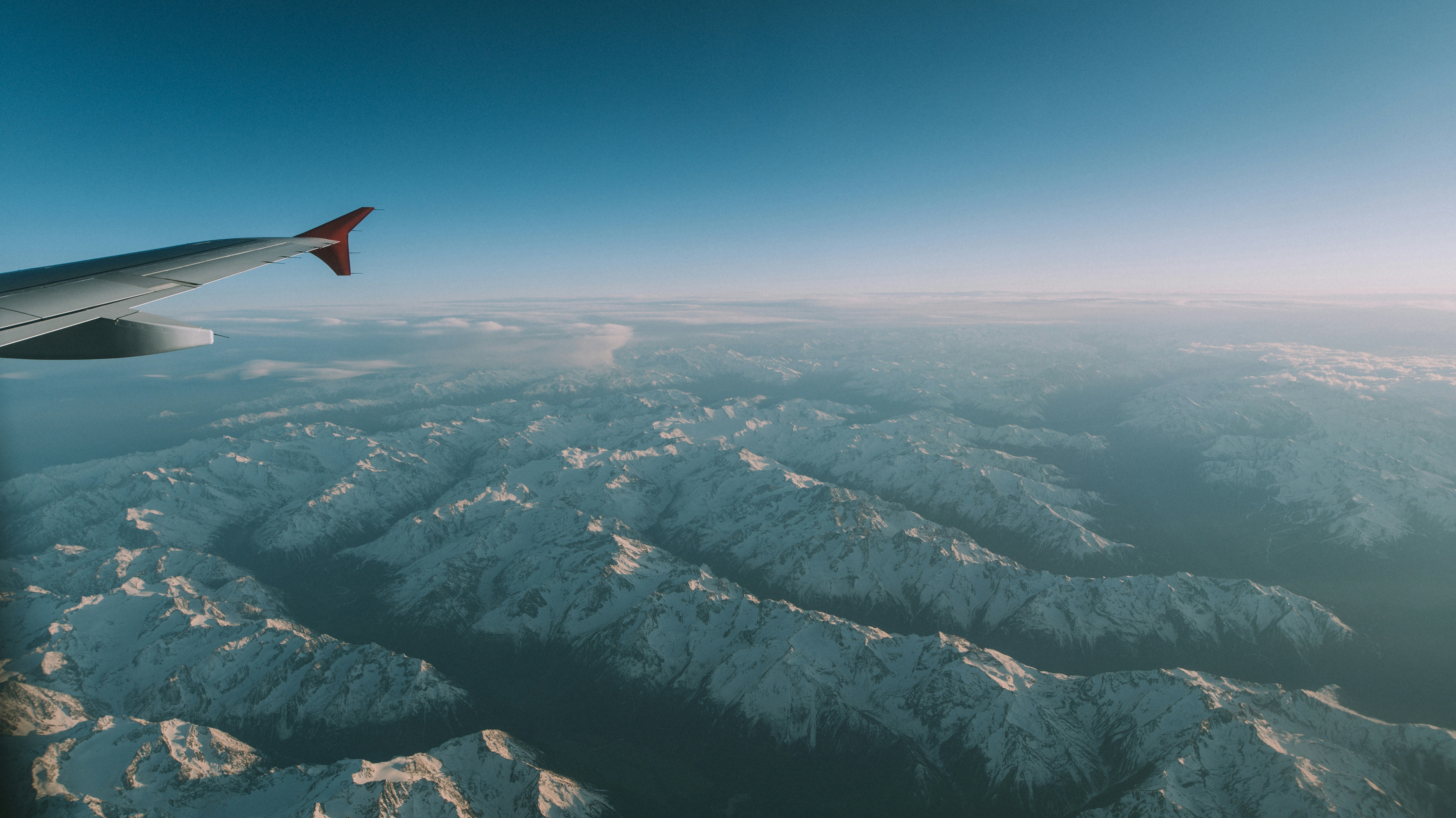 an airplane wing over snowy mountains
