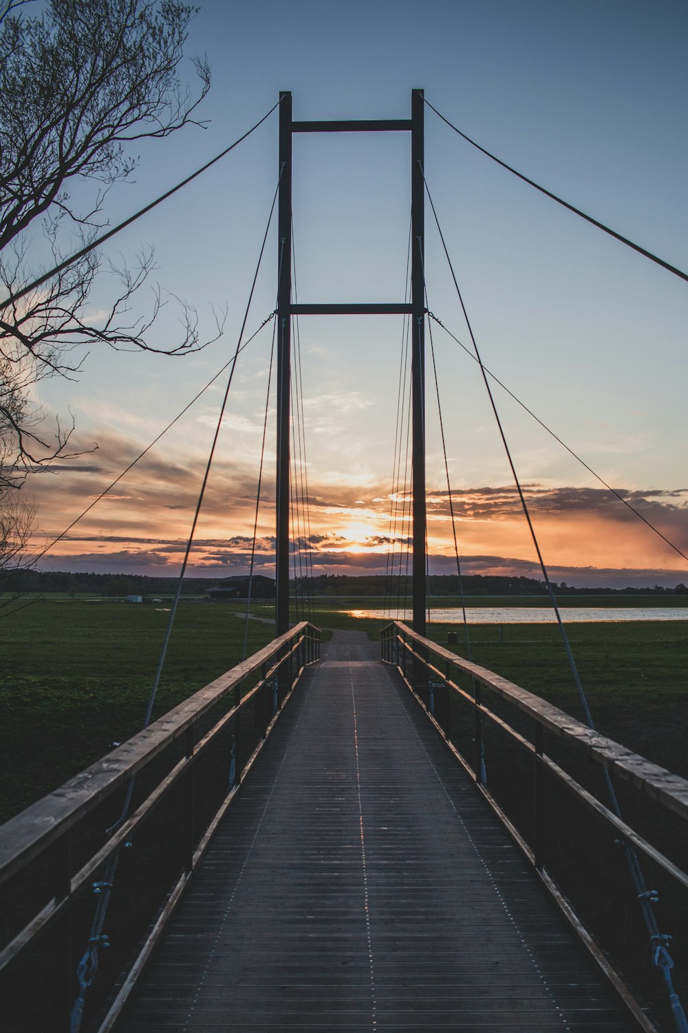 a wooden bridge with a sunset in the background with Humber Bridge in the background