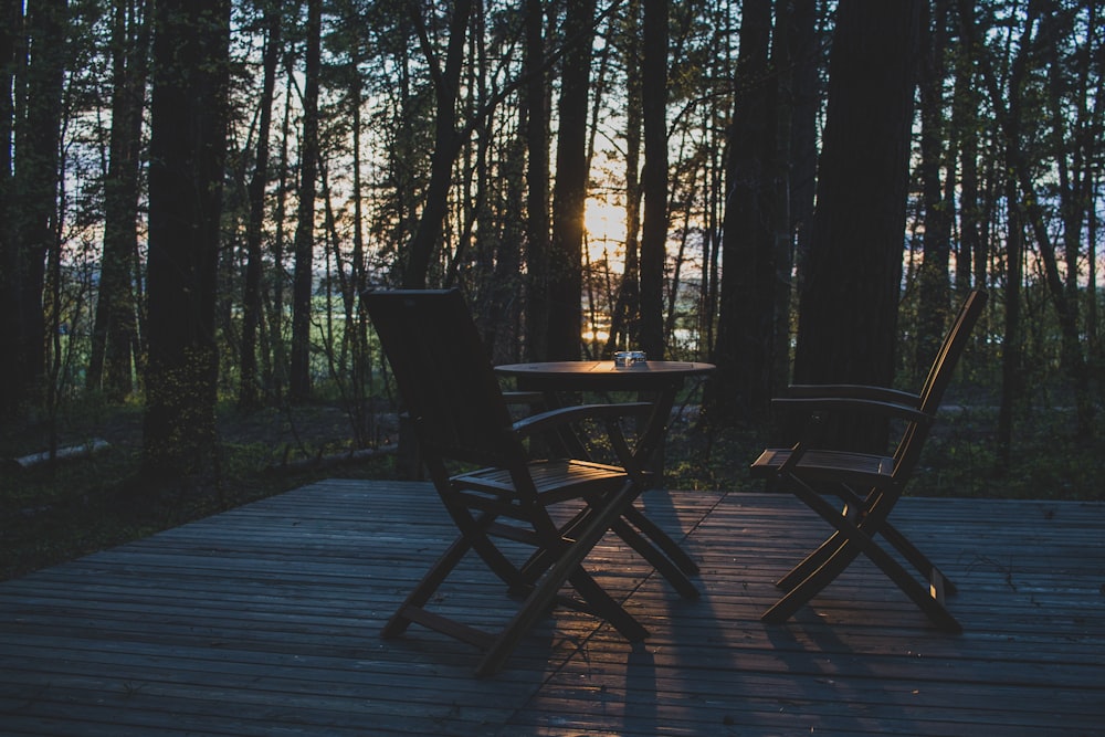 a table and chairs on a wood deck in the woods