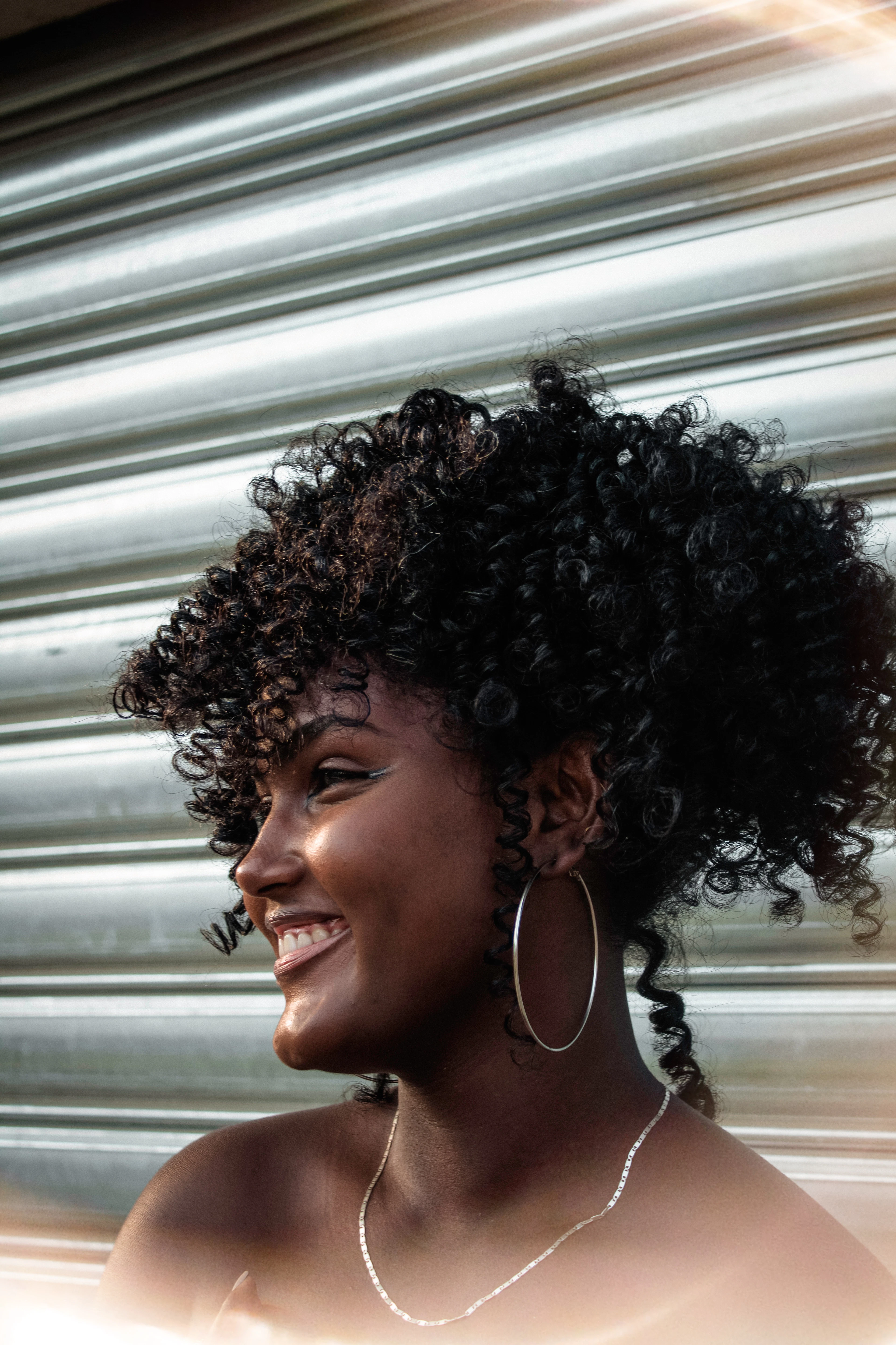 Smiling woman with a short, full curly cut and gold hoop earrings