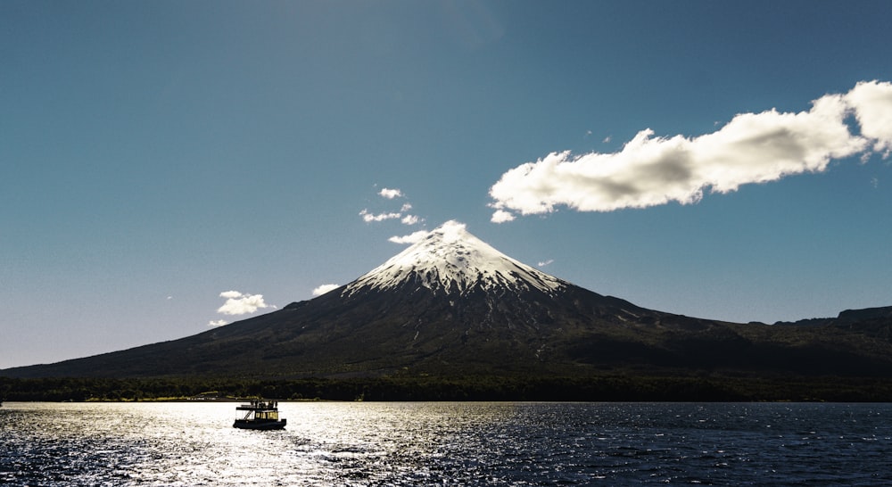 a boat on the water with a mountain in the background