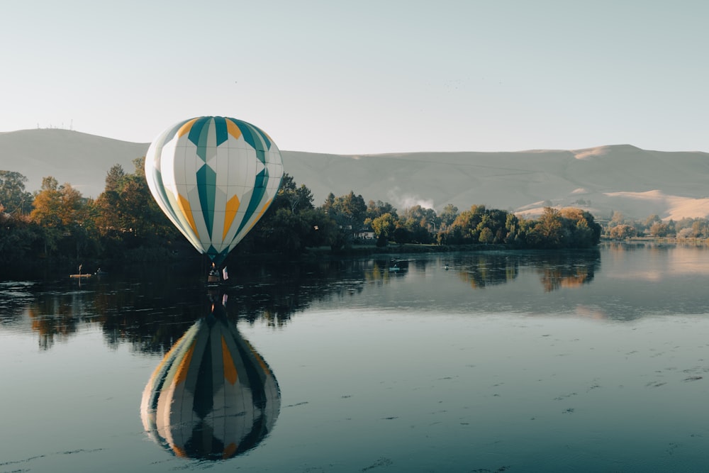 a hot air balloon floating over a lake