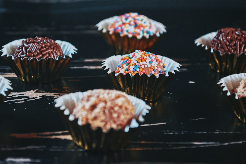 cupcakes with frosting and sprinkles on a black surface