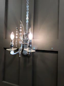 A black metal wall sconce illuminating a textured wall with subtle elegance.