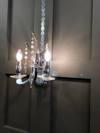 A black metal wall sconce illuminating a textured wall with subtle elegance.