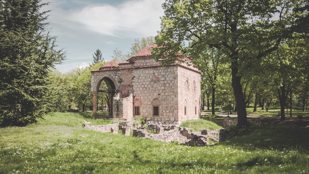 a stone building with a red roof surrounded by trees