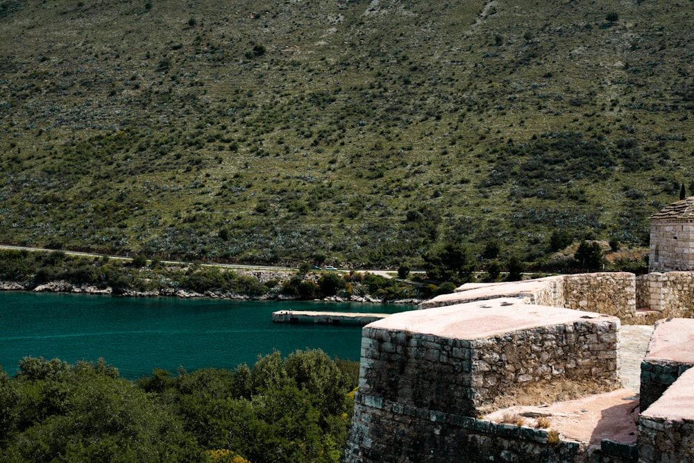 a stone wall with a lake and trees in the background