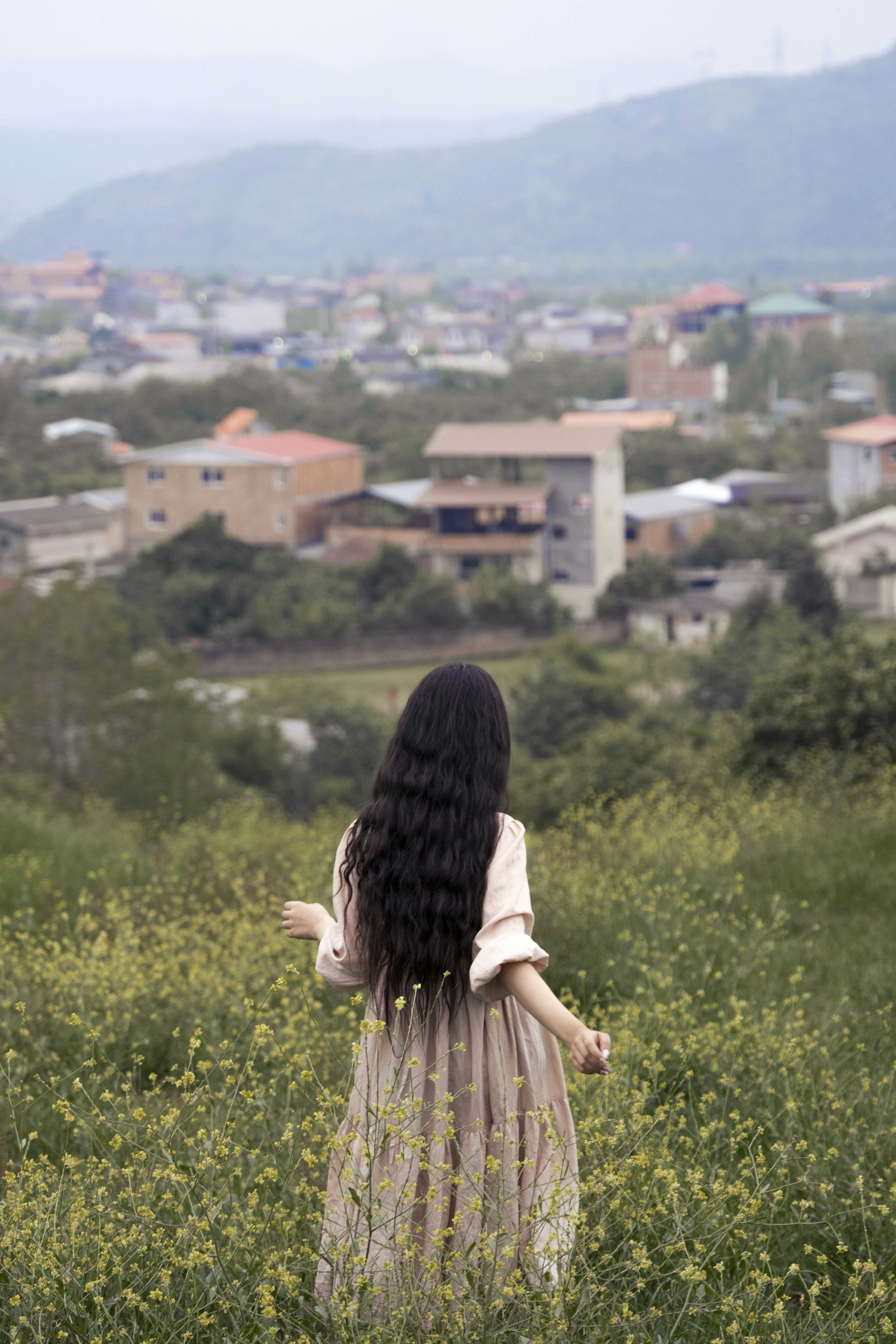 A person standing in a field of flowers with a town in the background ...
