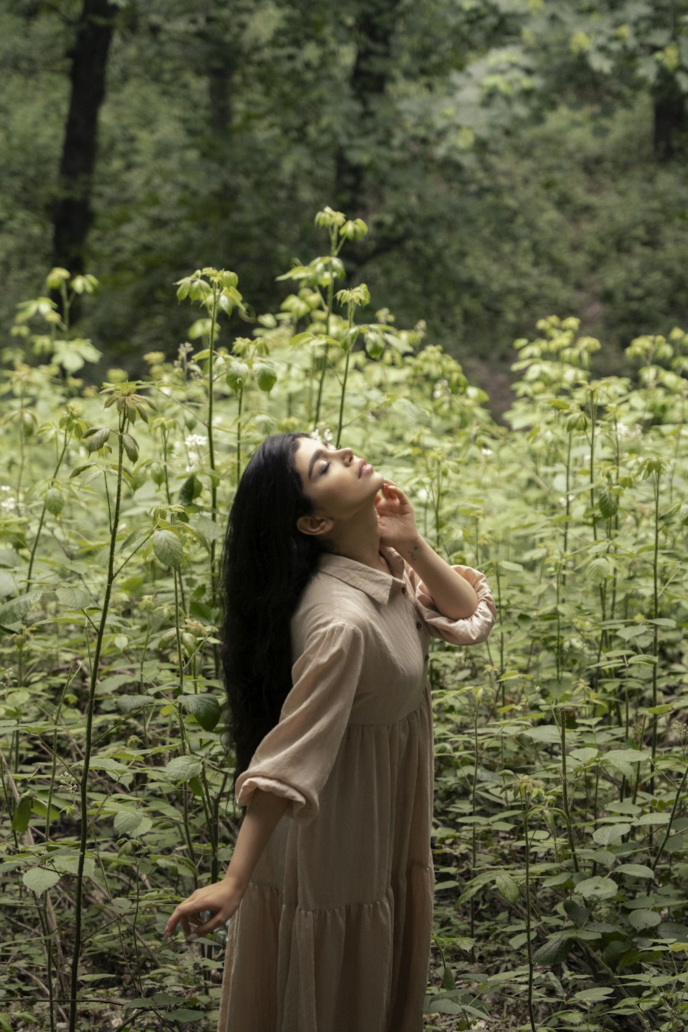 a woman in a dress standing in a field of plants