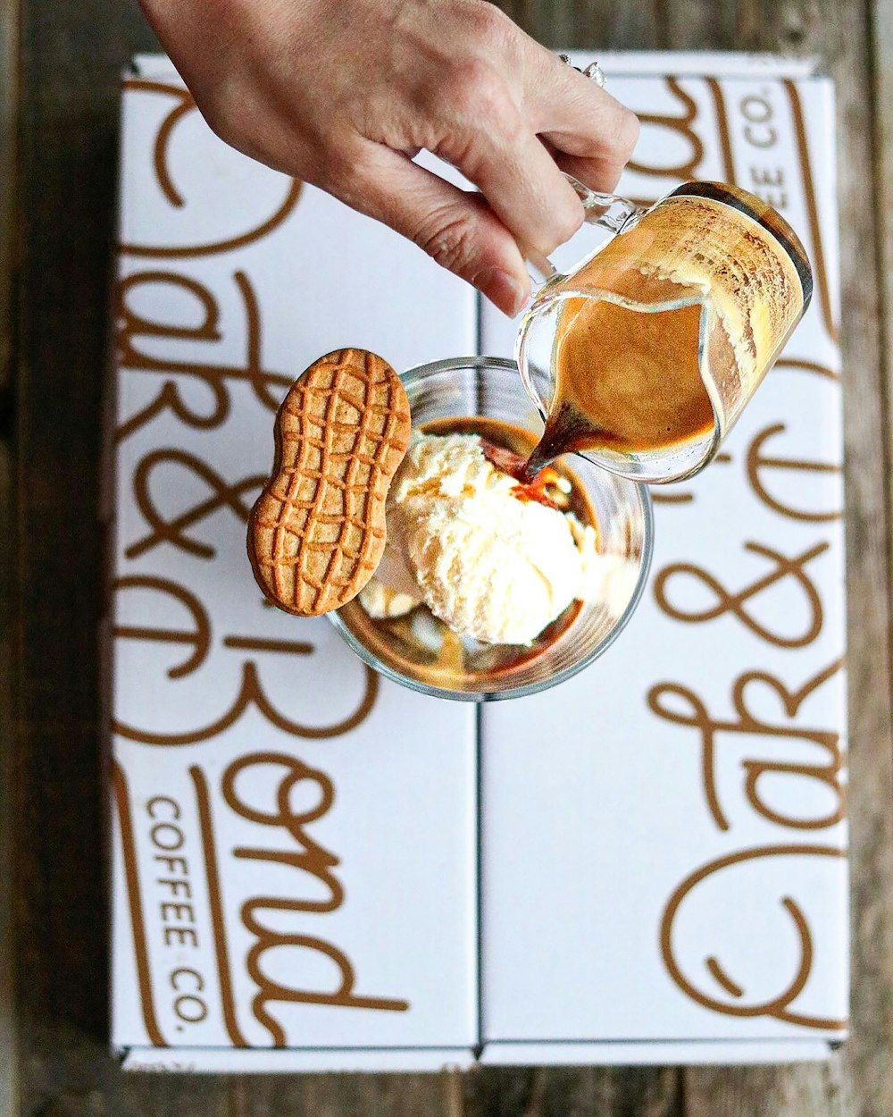 a hand holding a glass of ice cream