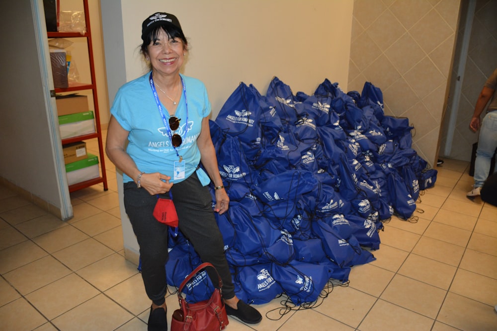 a person sitting on a pile of blue bags