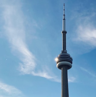 The iconic Monas tower rising against a clear blue sky, with visitors gathered around its base.
