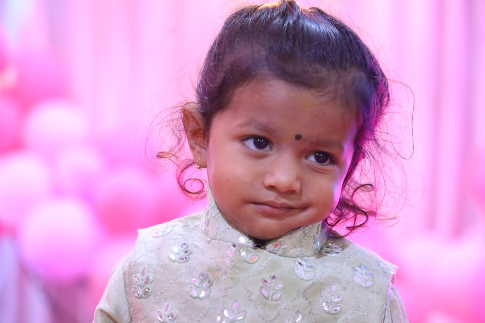 a baby with a pink flower in her hair