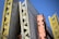 A structural framework composed of large, vertical concrete panels supported by wooden and metal beams. The beams are prominently yellow and orange, creating contrasting lines and textures against a clear blue sky.