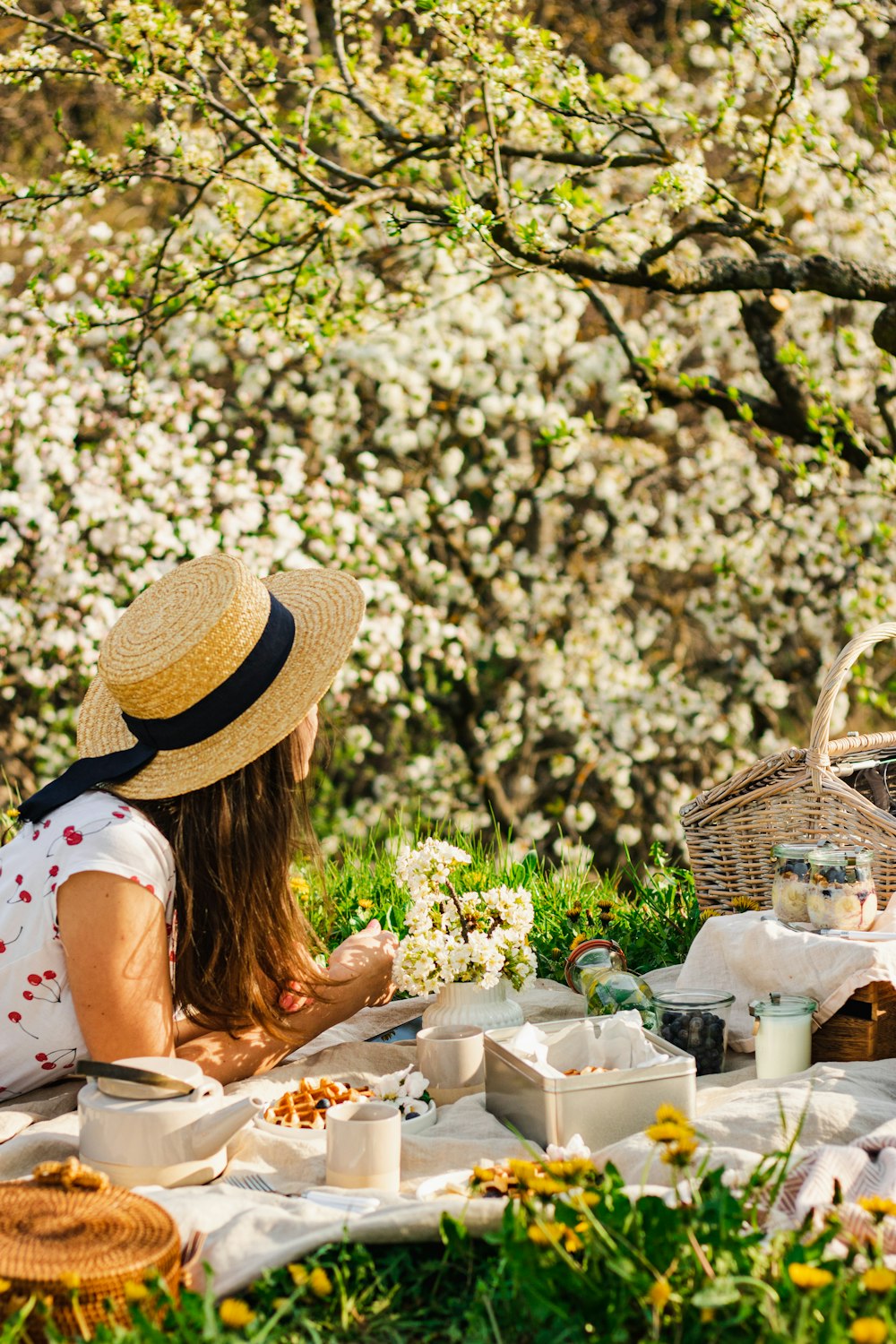 a woman sitting at a table with food and flowers