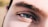 A close-up view of a person's eye featuring thick eyebrows and long lashes. The image highlights the intricate details of the skin texture and the natural eye color.
