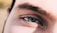A close-up view of a person's eye featuring thick eyebrows and long lashes. The image highlights the intricate details of the skin texture and the natural eye color.
