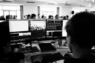 a man sitting at a desk with several monitors
