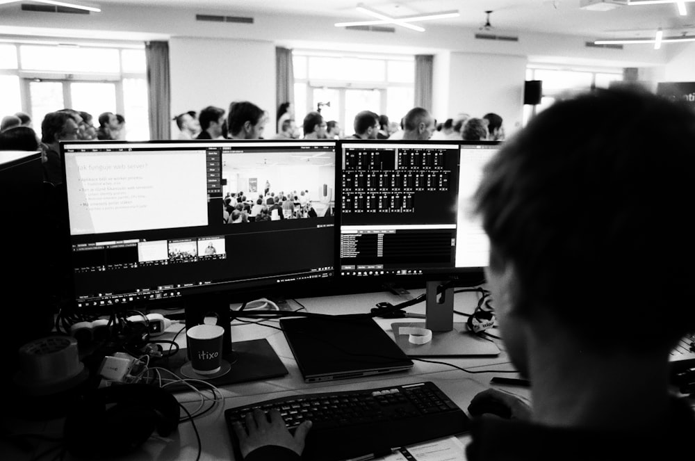 a man sitting at a desk with several monitors