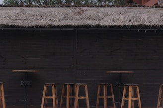 Rustic wooden bar setup with a single bartender serving drinks under warm string lights.