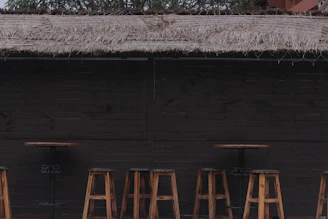A stylish rattan high bar stool with a comfortable cushion, positioned beside a garden bar setup.