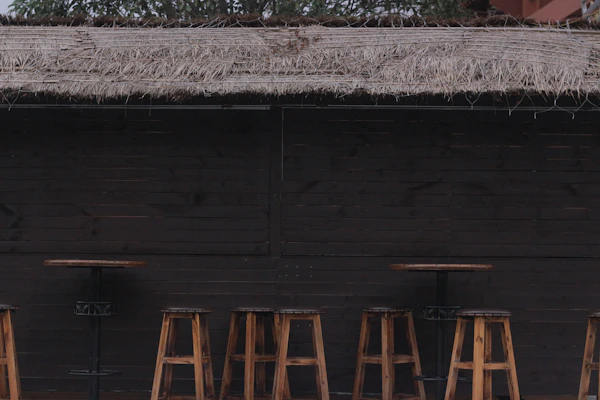 A stylish rattan high bar stool with a comfortable cushion, positioned beside a garden bar setup.
