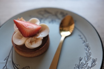 Hands delicately placing a handcrafted sweet on a minimalist plate with champagne gold details.