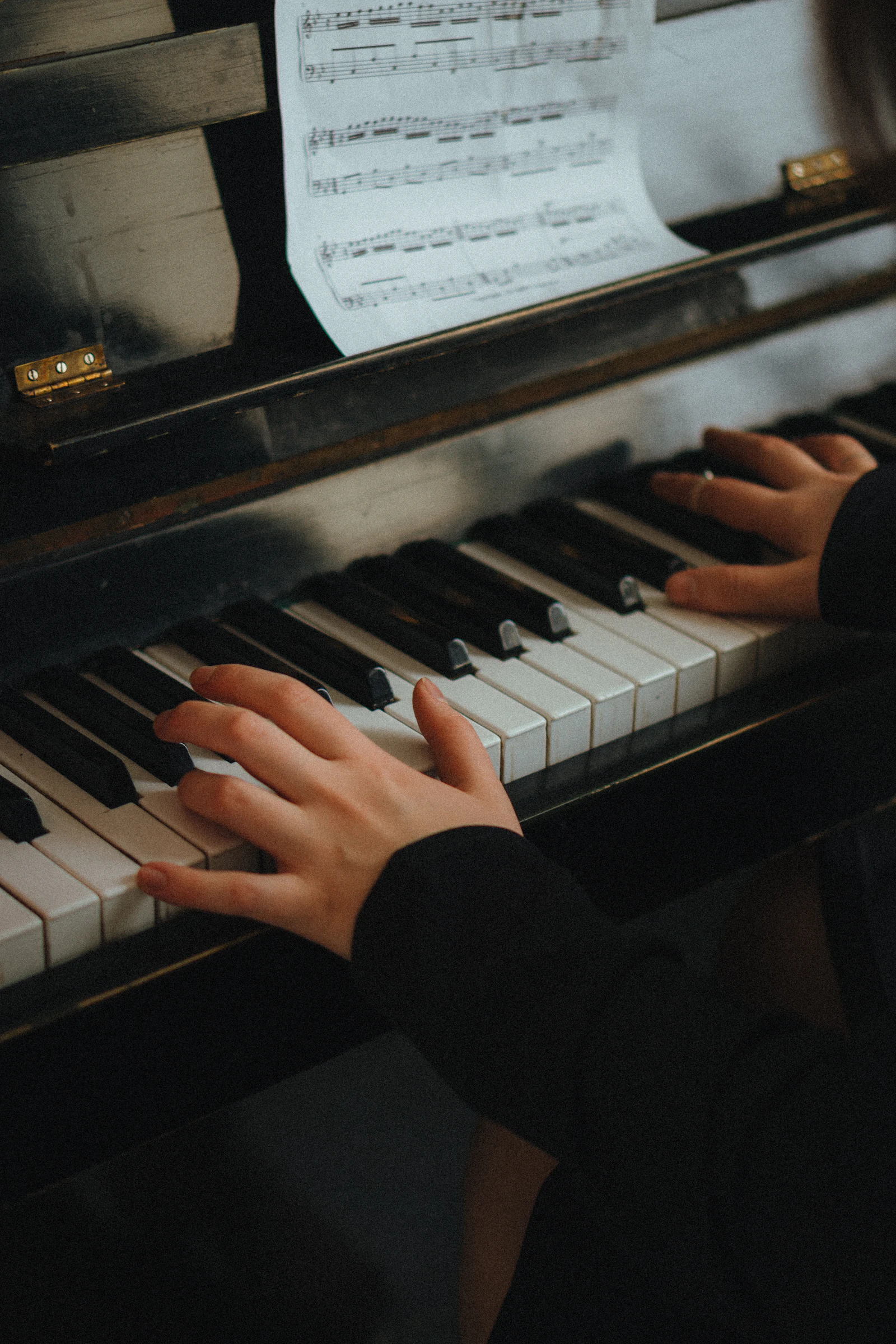 Hands on the piano beside a written note