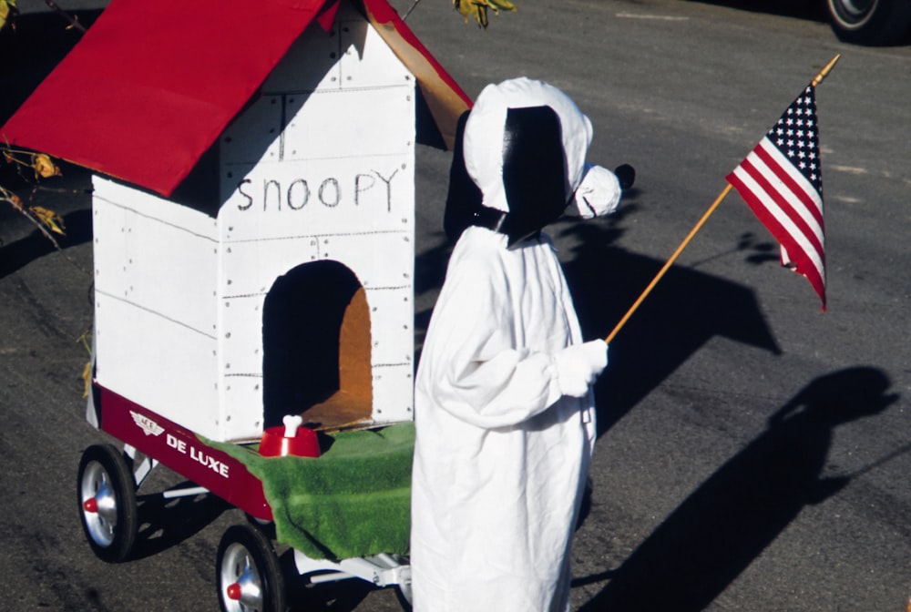 a person in a white suit holding a flag next to a cart