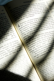 An open ancient book with golden light shining on its pages in a dark chapel