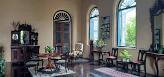 Elegant parlor room bathed in soft sunlight, vintage furnishings arranged for an intimate gathering.