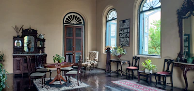 Elegant parlor room bathed in soft sunlight, vintage furnishings arranged for an intimate gathering.