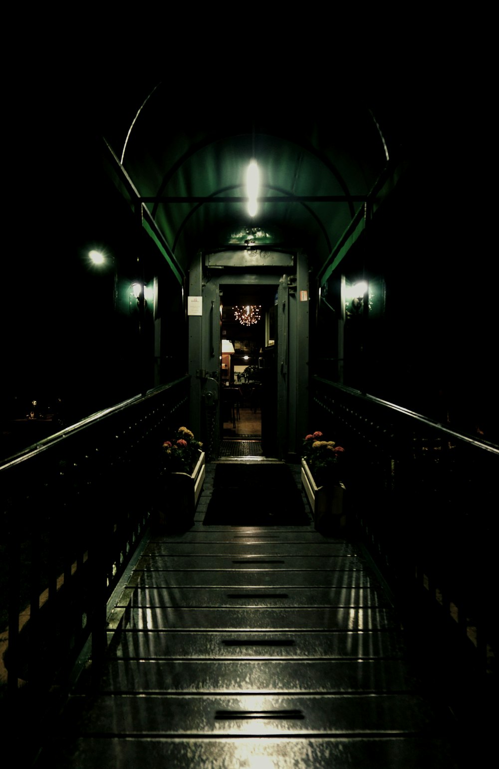 a long dark hallway with a green light at the end